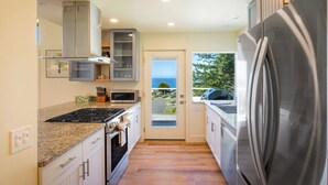 A modern kitchen with stainless steel appliances, a microwave, and a gas stove. - Cottage by the Sea (Whitethorn)