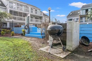 Ein Wohngebiet mit Grill, blauer Bank und einem Betonbau.