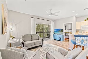 Ein modernes Wohnzimmer mit einer Couch, einem Essbereich mit Tisch und Stühlen sowie einer Küche im Hintergrund.
