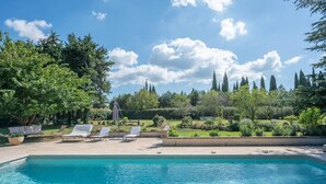 Ein Schwimmbad mit Liegestühlen und Blick auf einen Garten.