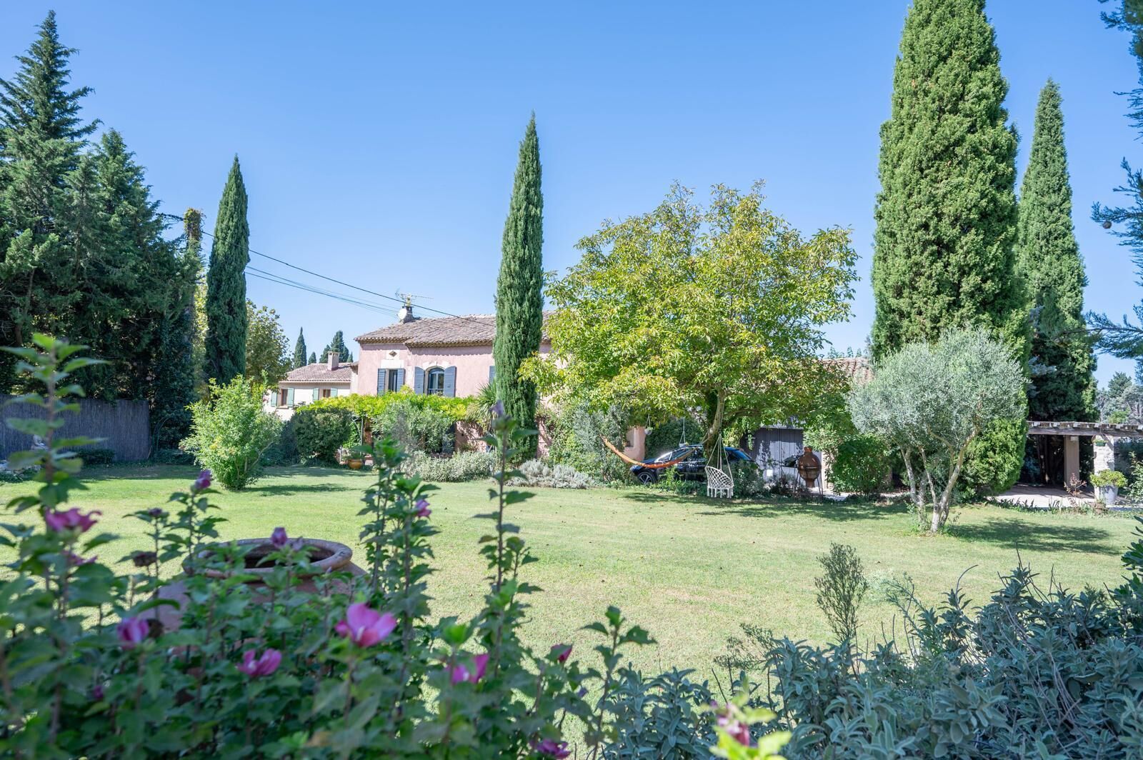 Una casa con jardín, hamaca y pérgola.