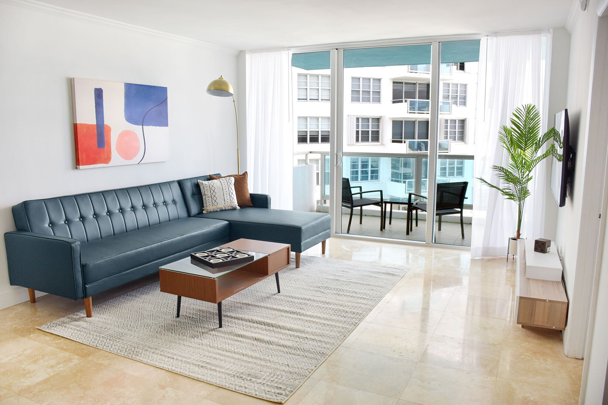Una sala de estar moderna con un sofá seccional, una mesa de centro y un ventanal con vistas a un edificio.