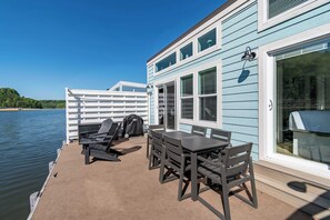 A deck with a table and chairs, a grill, and a view of the water.