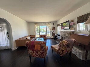 A living room with a sofa, patterned chairs, a coffee table, a fireplace, a television, and a piano. - 2-bedroom Duplex,  in lovely Los Angeles with AC (Los Angeles)