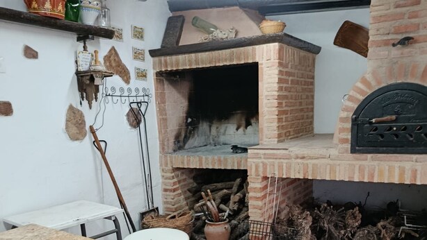 Eine rustikale Küche mit Backofen, einem Holztisch und einem Musterfußboden.