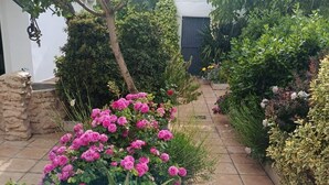 En trädgård med ett stort utbud av växter och blommor, en stenmur och en gång som är belagd med plattor.