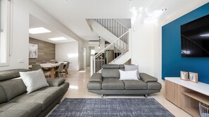 A modern living room with a sofa, a coffee table, and a TV on a stand. - Tides Edge in Capel Sound (Capel Sound)