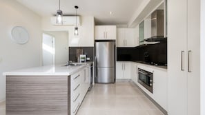 A modern kitchen with a central island, stainless steel appliances, and white cabinetry. - Tides Edge in Capel Sound (Capel Sound)