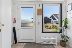 A white door with a window, a white bench, a potted plant, and a fire extinguisher. - Holiday home in Vorupør near sea and nature (Thisted)