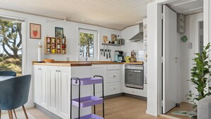 Une cuisine moderne avec des armoires blanches, un plan de travail en bois et un chariot de rangement violet.