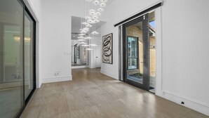 Un pasillo moderno con suelo de madera, puertas de cristal y arte abstracto en las paredes.