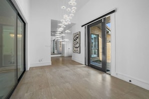 Un pasillo moderno con suelo de madera, puertas de cristal y arte abstracto en las paredes.