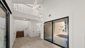 Un interior moderno con una escalera, un vidrio que da al exterior y una lámpara colgante.