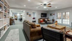 A spacious living area with a sofa, coffee table, and bookshelf. - Hill Country Family & Pickleball Retreat (Ingram)