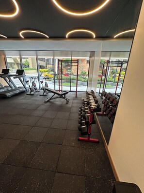 Ett gym med träningsutrustning, en stång för chins och en fönstervy ut mot omvärlden.