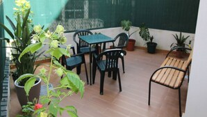 A patio with a table and chairs, potted plants, and a green fence. - Aveiro Apartment with Patio (Aveiro)