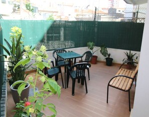 Eine Terrasse mit Tisch und Stühlen, Blumentöpfen und einem grünen Zaun.