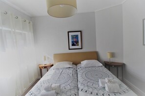 Ein Doppelbett mit gemusterten Bettbezügen, ein gerahmtes Bild an der Wand und zwei Nachttische mit Lampen.