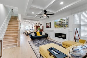 Un vaste salon comprenant un escalier, une cheminée et un coin repas.