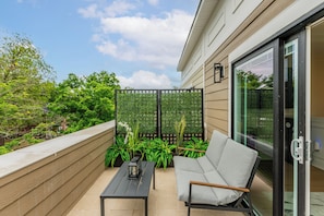Un balcon avec un canapé, une table et des plantes en pot.