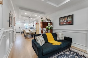 Un salon moderne avec un canapé vert foncé, un plaid jaune et un tapis à motifs.
