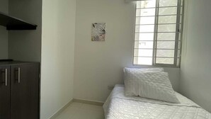 A bedroom with a bed, a window with blinds, a cabinet, and a wall-mounted artwork. - Comfortable apartment in Barranquilla, warmth of home, with pool, parking, gym and wifi. (Barranquilla)
