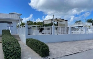 A white building with a covered outdoor area, a gated entrance, and a staircase leading to the entrance. - Key Largo 2BR Retreat | Pool & Boat Ramp (Key Largo)
