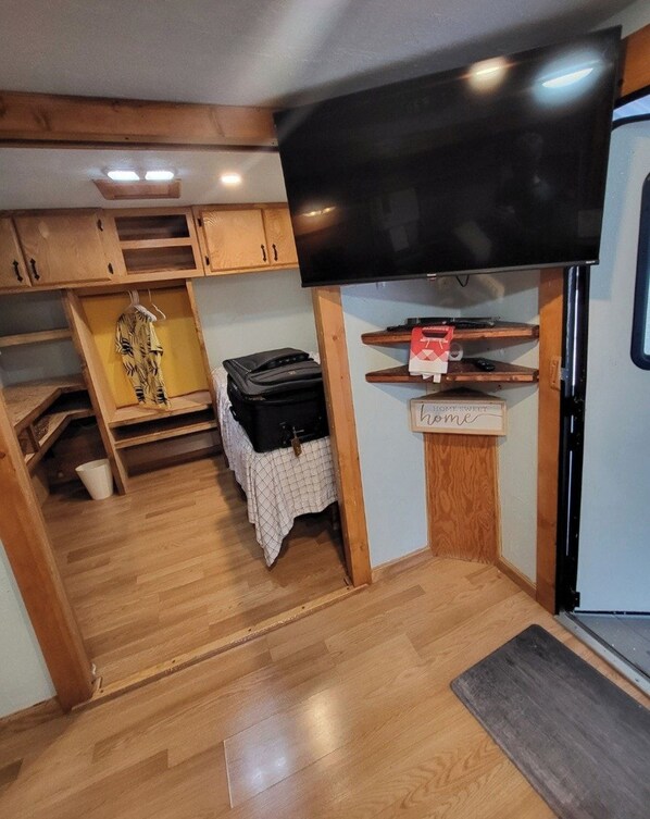 A compact living space with a television mounted above a wooden cabinet, a small refrigerator, and a bench. - Key Largo 2BR Retreat | Pool & Boat Ramp (Key Largo)