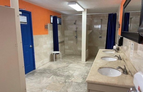 A bathroom with two sinks, a shower area, and a blue door. - Key Largo 2BR Retreat | Pool & Boat Ramp (Key Largo)