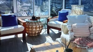 Et solarium med udsigt over byen, møbleret med stole, et bord og dekorative puder.