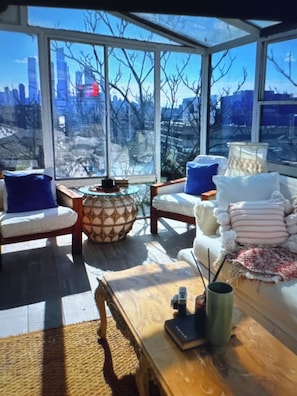 A conservatory with a city view, furnished with chairs, a table, and decorative pillows. - Exclusive 6Bed5Bath Penthouse • NYC view • Parking (Weehawken Township)