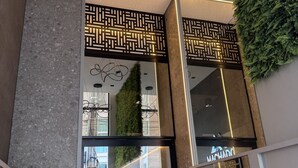 Ein moderner Hotel Eingang mit Glastür, Tastatur und einem Schild mit der Aufschrift 'Vila Premium'.