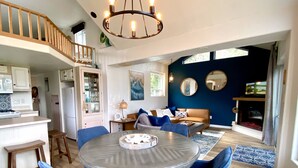 Eine moderne Küche mit Essbereich, einer Treppe und einem Wohnzimmer mit Kamin.