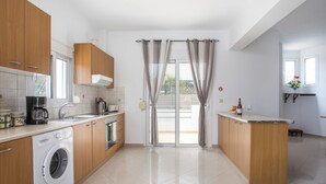 A modern kitchen with a washing machine, a coffee maker, and a sink. - Ennisfree Villa (Kiotari)