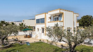 A modern two-story building with a patio area, outdoor seating, and a small play area. - Ennisfree Villa (Kiotari)