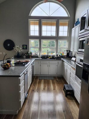 Eine Küche mit großem Fenster, weißen Schränken und Holzboden.