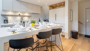 A modern kitchen with a central island, white cabinetry, and a marble backsplash. - 3BDR Luxury Ski-In&Out in|Prime Location|Valet Bike&Ski storage (Whistler)