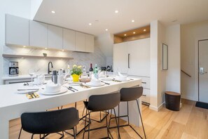 A modern kitchen with a central island, white cabinetry, and a marble backsplash. - 3BDR Luxury Ski-In&Out w/Pool&Hot Tub|Prime Loc. (Whistler)