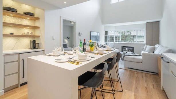 A modern kitchen with a central island, dining area, and a cozy seating space with a fireplace. - 3BDR Luxury Ski-In&Out in|Prime Location|Valet Bike&Ski storage (Whistler)