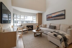A modern living room with a sofa, armchair, coffee table, fireplace, and large windows. - 3BDR Luxury Ski-In&Out w/Pool&Hot Tub|Prime Loc. (Whistler)