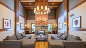 A spacious lobby with two sofas facing a fireplace, a chandelier, and framed artwork on the walls. - 3BDR Luxury Ski-In&Out in|Prime Location|Valet Bike&Ski storage (Whistler)