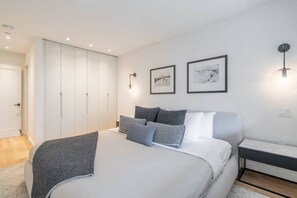 A bedroom with a bed, a wardrobe, a nightstand, and two framed pictures on the wall. - 3BDR Luxury Ski-In&Out w/Pool&Hot Tub|Prime Loc. (Whistler)