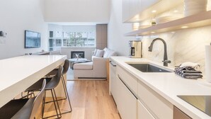 A modern kitchen with a central island, a built-in oven, and a large window providing natural light. - 3BDR Luxury Ski-In&Out in|Prime Location|Valet Bike&Ski storage (Whistler)