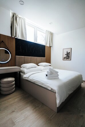 Un dormitorio moderno con cama, mesita de noche y espejo.