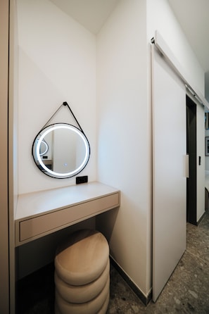 Un baño moderno con un espejo redondo, un tocador y un taburete.