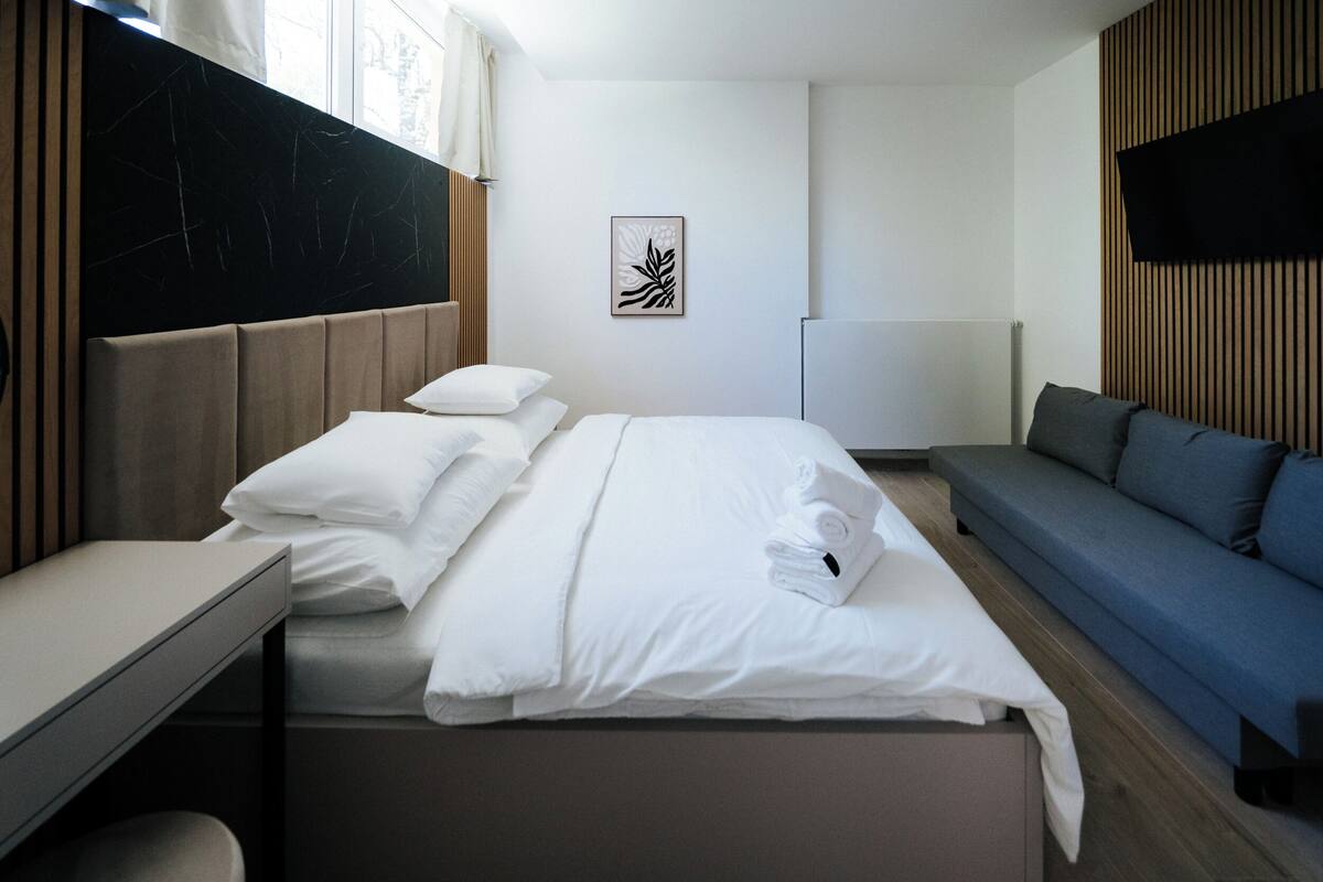 Ein modernes Hotelzimmer mit Bett, Nachttisch und einer Couch.