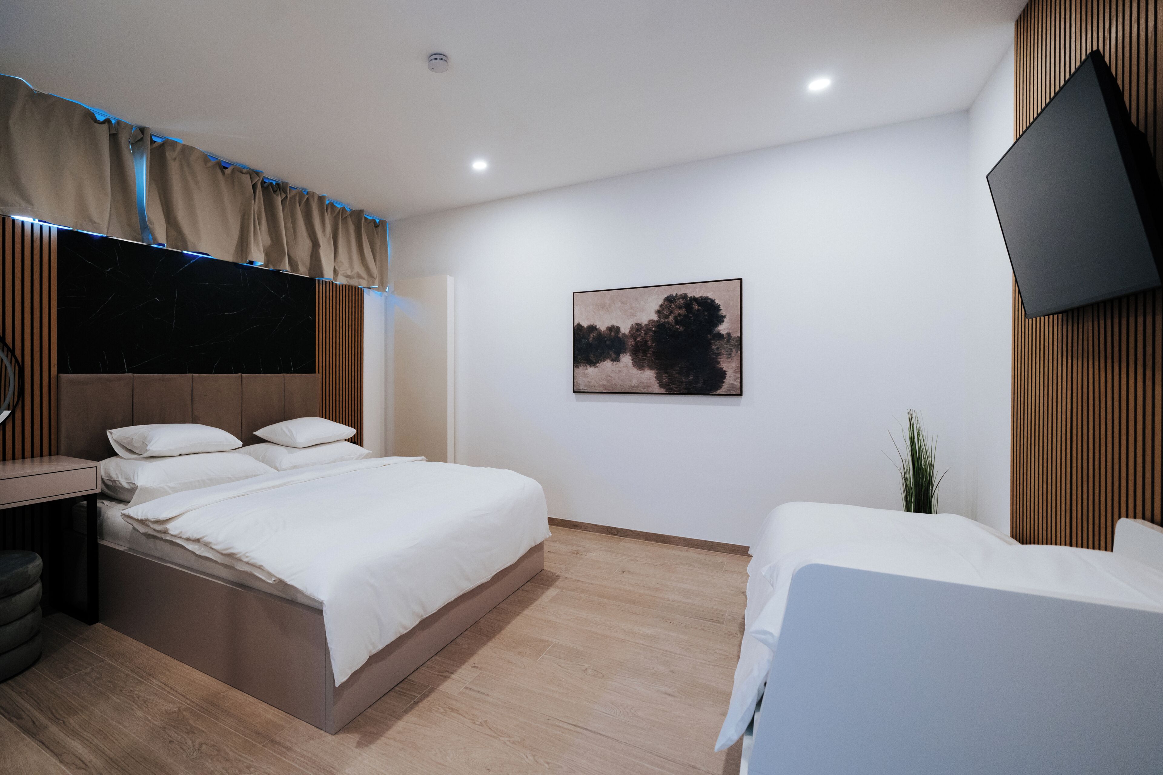 Una habitación de hotel moderna con una cama, una mesita de noche y un televisor montado en la pared.
