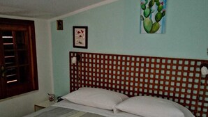 Ein Bett mit einer gestreiften Tagesdecke, Kissen und gerollten Handtüchern.