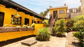 Un patio con edificios amarillos, una escalera y varias plantas en macetas.