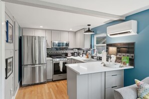 Une cuisine moderne dotée d’appareils électroménagers en acier inoxydable, d’un plan de travail blanc et d’un mur d’accent bleu.